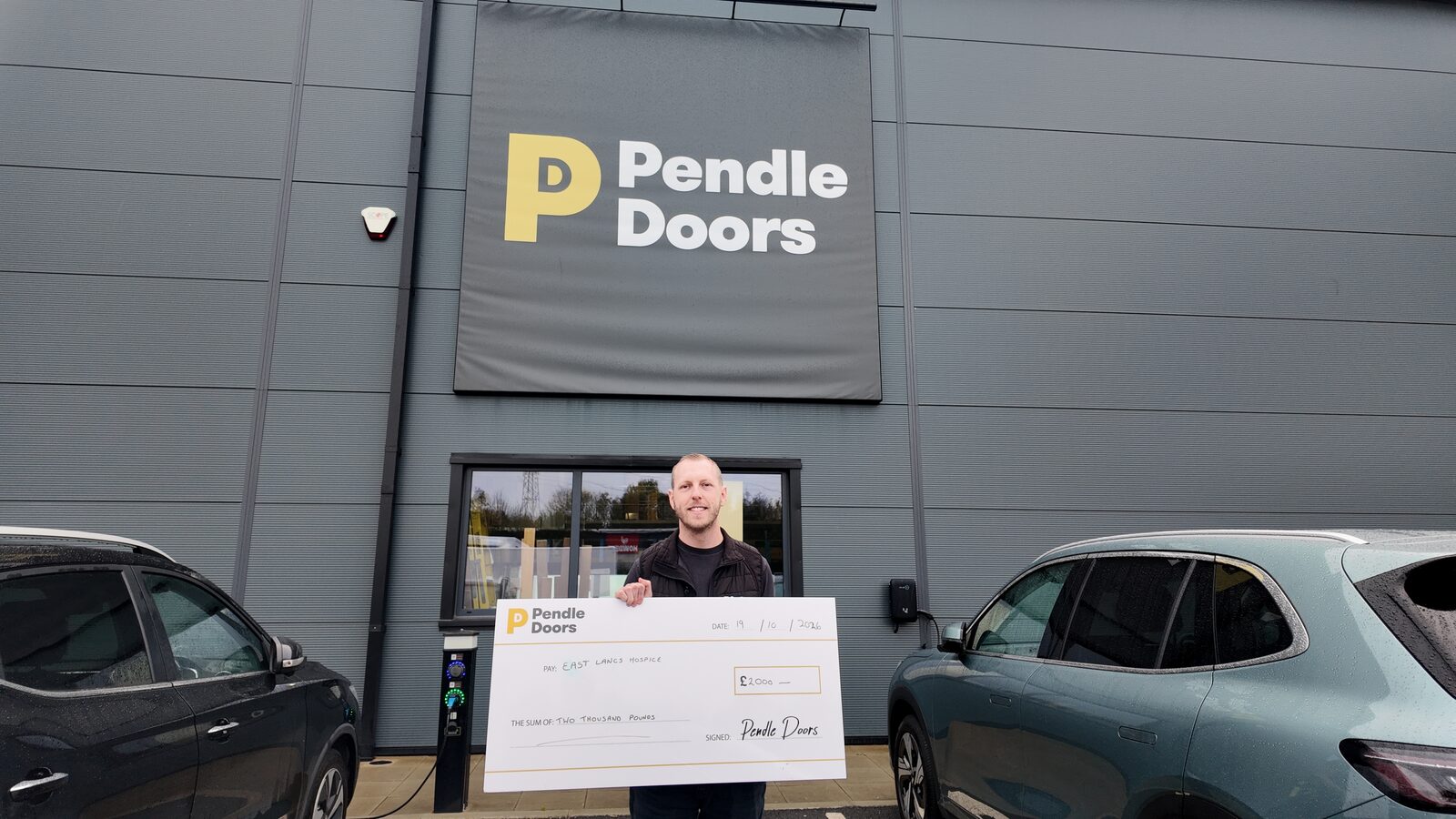 Pendle Doors £2,000 donation cheque for East Lancs Hospice outside the Pendle Doors building